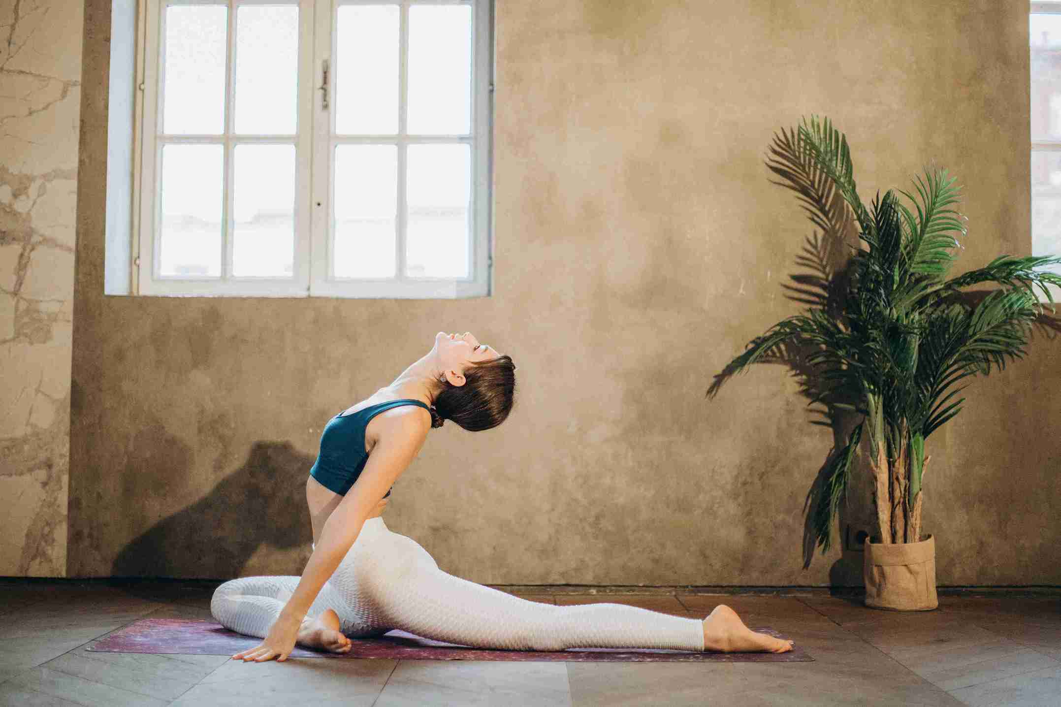 Woman performing a deep yoga stretch indoors on a mat during a 30-day yoga challenge for beginners.
